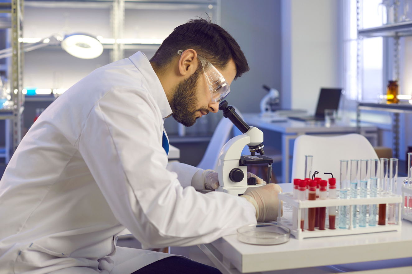 Scientist Looking in Microscope While Doing Research in Biotech Science Laboratory
